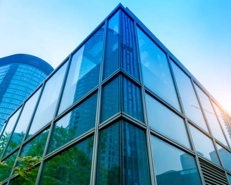 a glass building with trees and blue sky